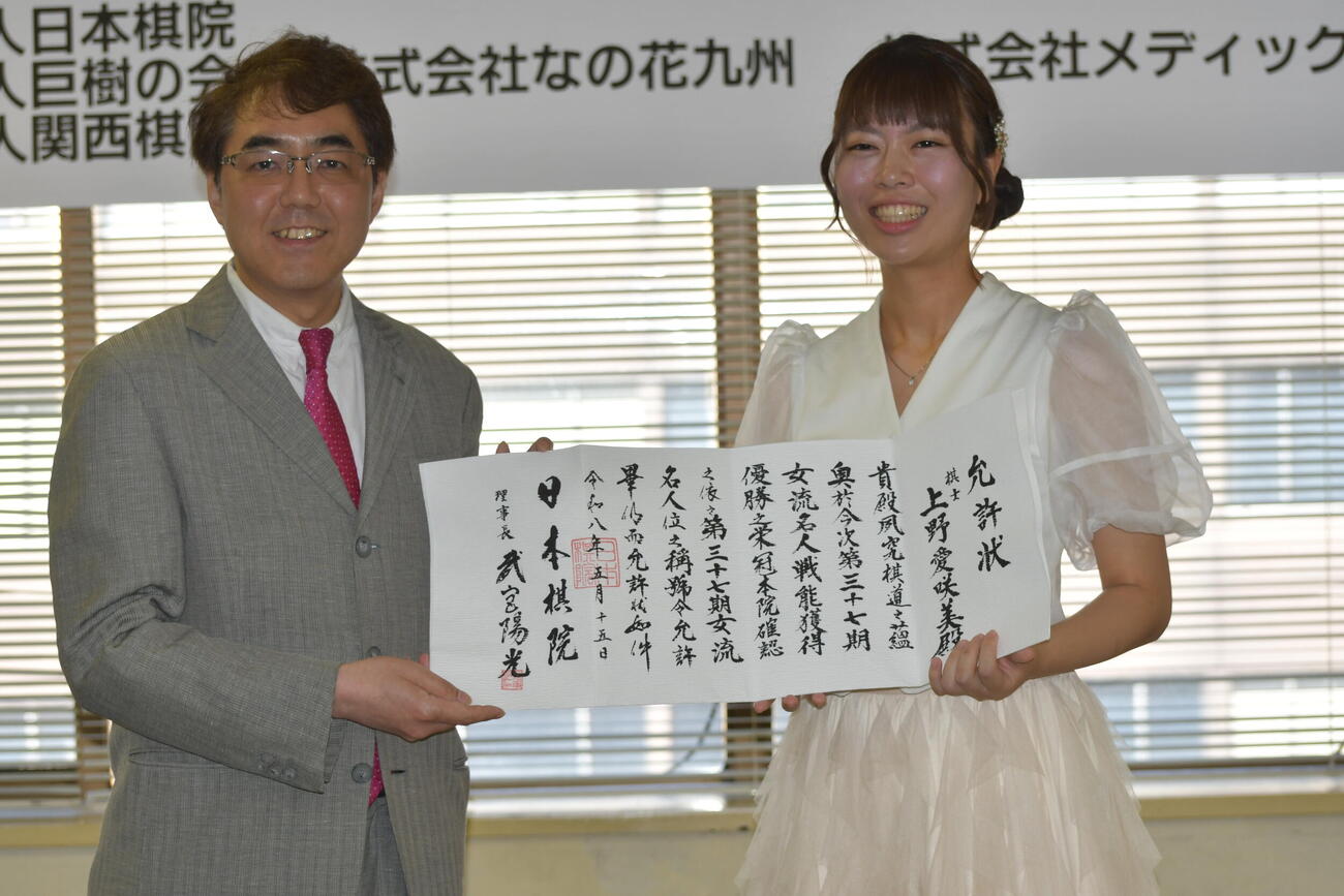 日本棋院の武宮陽光理事長（左）から渡された允許（いんきょ）状を手にする上野愛咲美女流名人