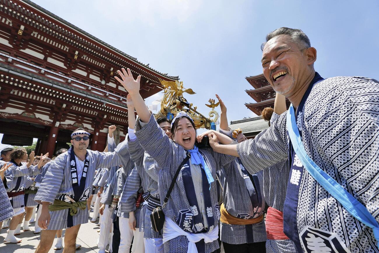 浅草神社の三社祭で、かけ声に合わせて笑顔でみこしを担ぐ人たち（共同）