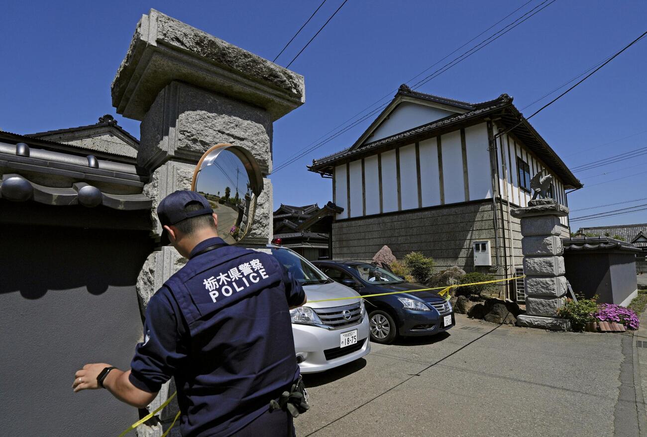 強盗殺人事件現場の住宅に規制線を張る警察官＝17日午前9時52分、栃木県上三川町(共同)