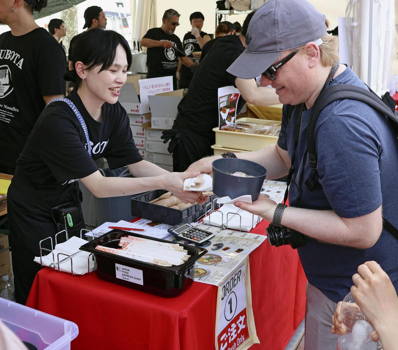23日、ドイツ・デュッセルドルフの「日本デー」で、ラーメンを受け取る男性（共同）