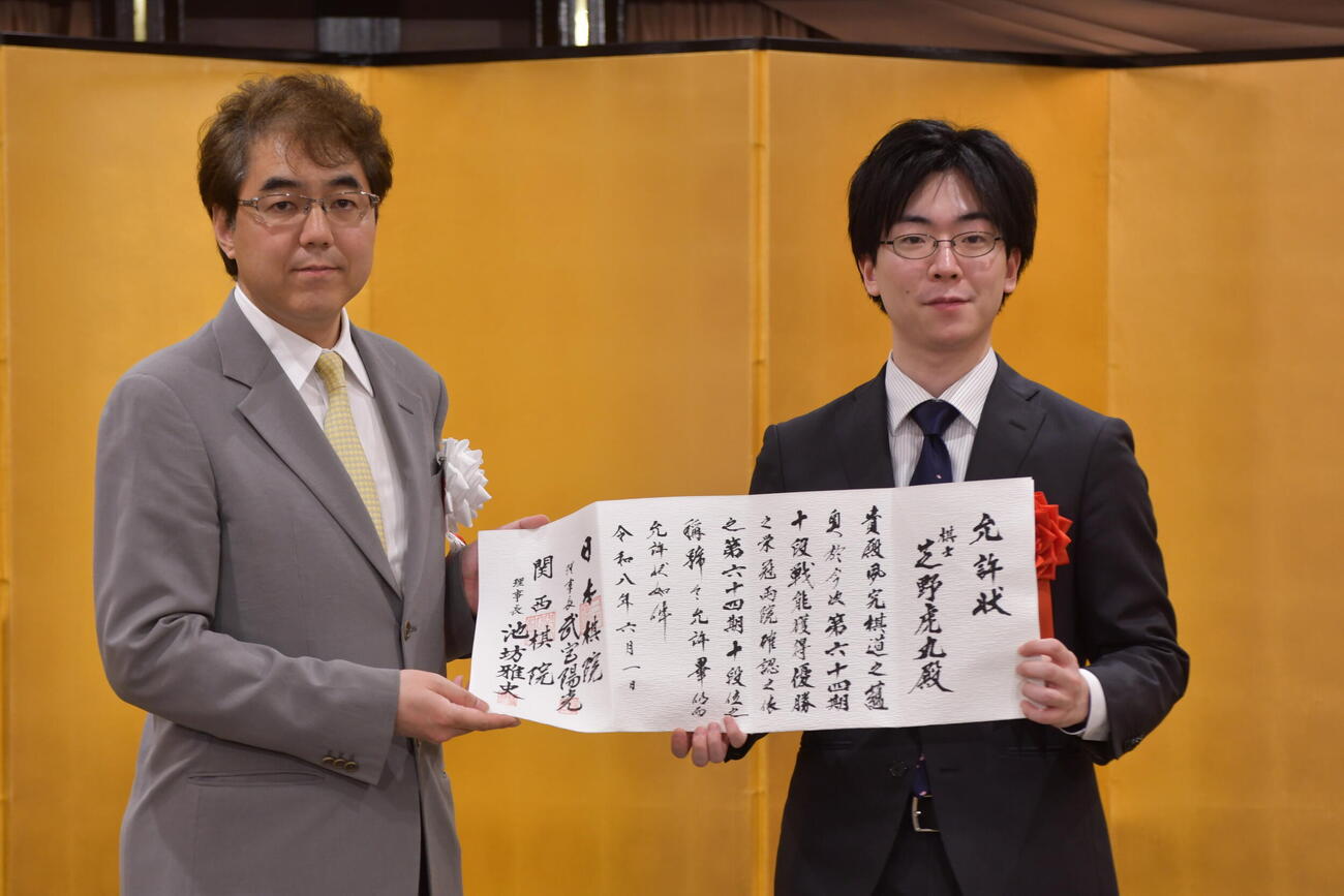 就位式で日本棋院の武宮陽光理事長（左）から允許（いんきょ）状を渡された芝野虎丸十段