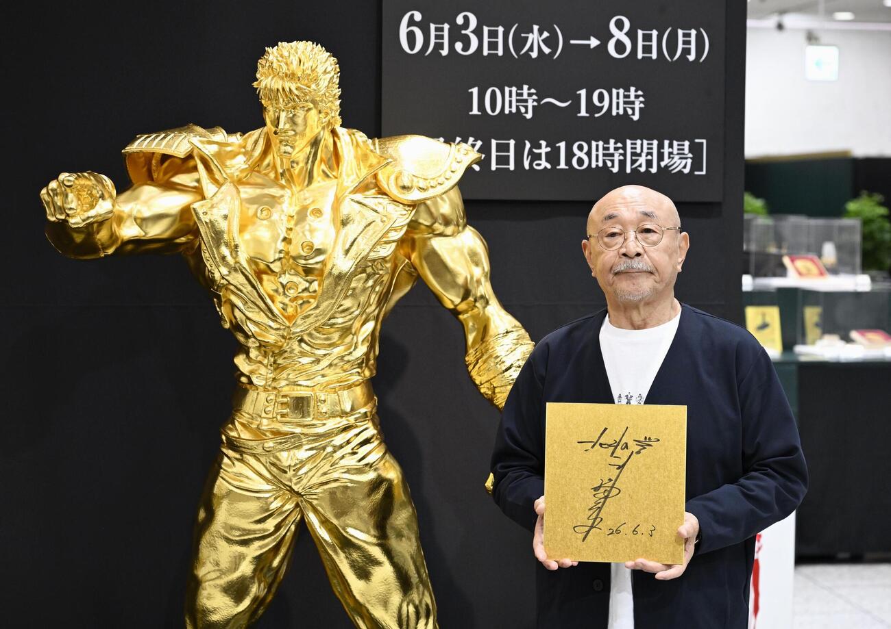 漫画「北斗の拳」の主人公ケンシロウの黄金像と写真に納まる、原作者の武論尊さん（共同）