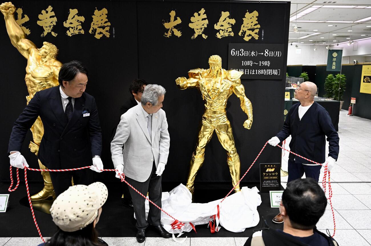 松坂屋名古屋店でお披露目された、漫画「北斗の拳」の主人公ケンシロウの黄金像。右端は原作者の武論尊さん（共同）