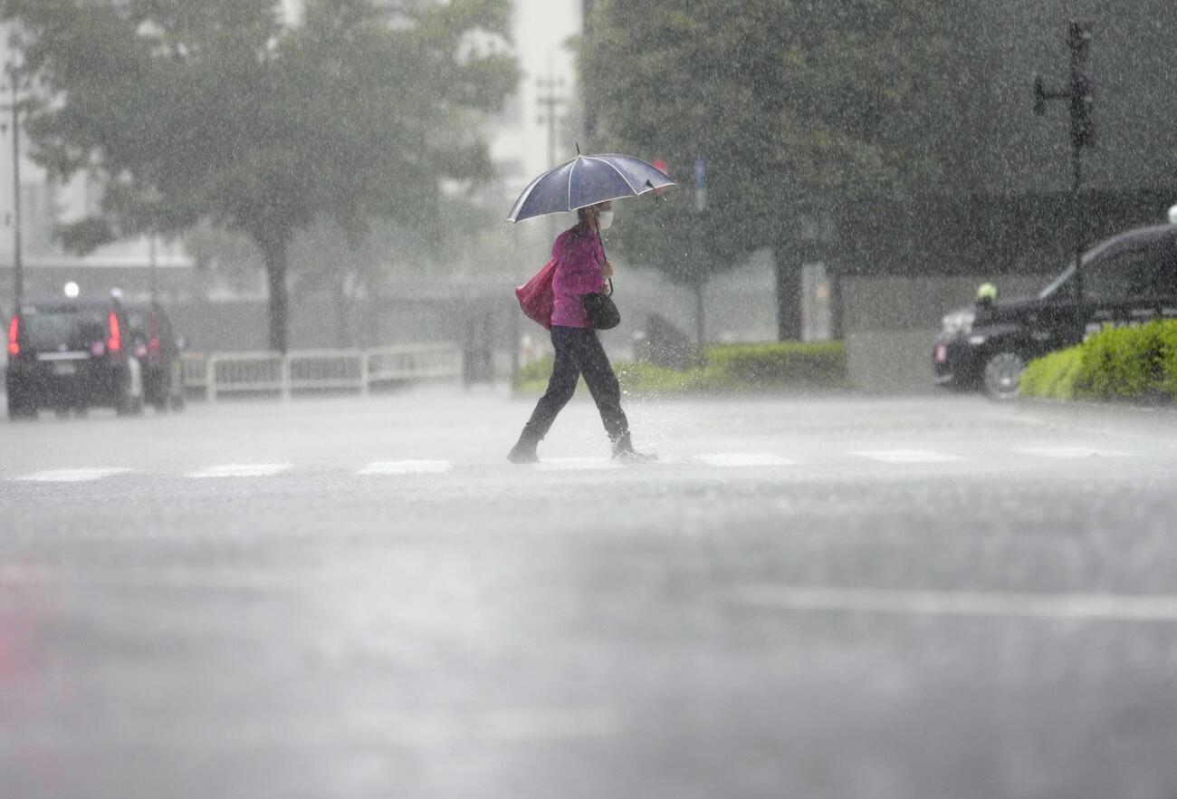 台風6号の影響による強い雨の中を歩く人、東京都千代田区（共同）