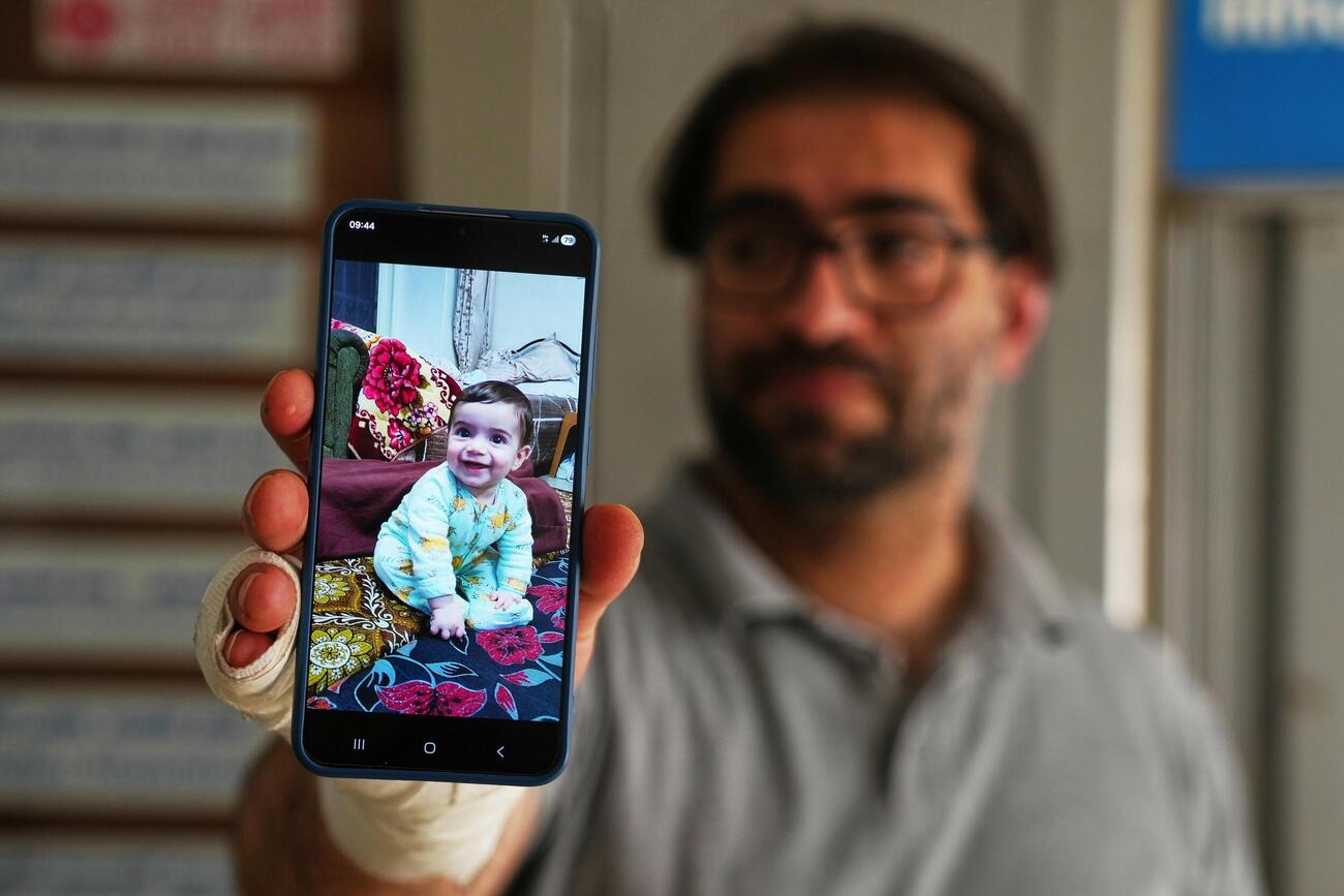 イスラエル軍の発砲で死亡した生後7カ月の乳児の写真を示す父親＝6日、パレスチナ自治区ヨルダン川西岸ヘブロン（AP＝共同）