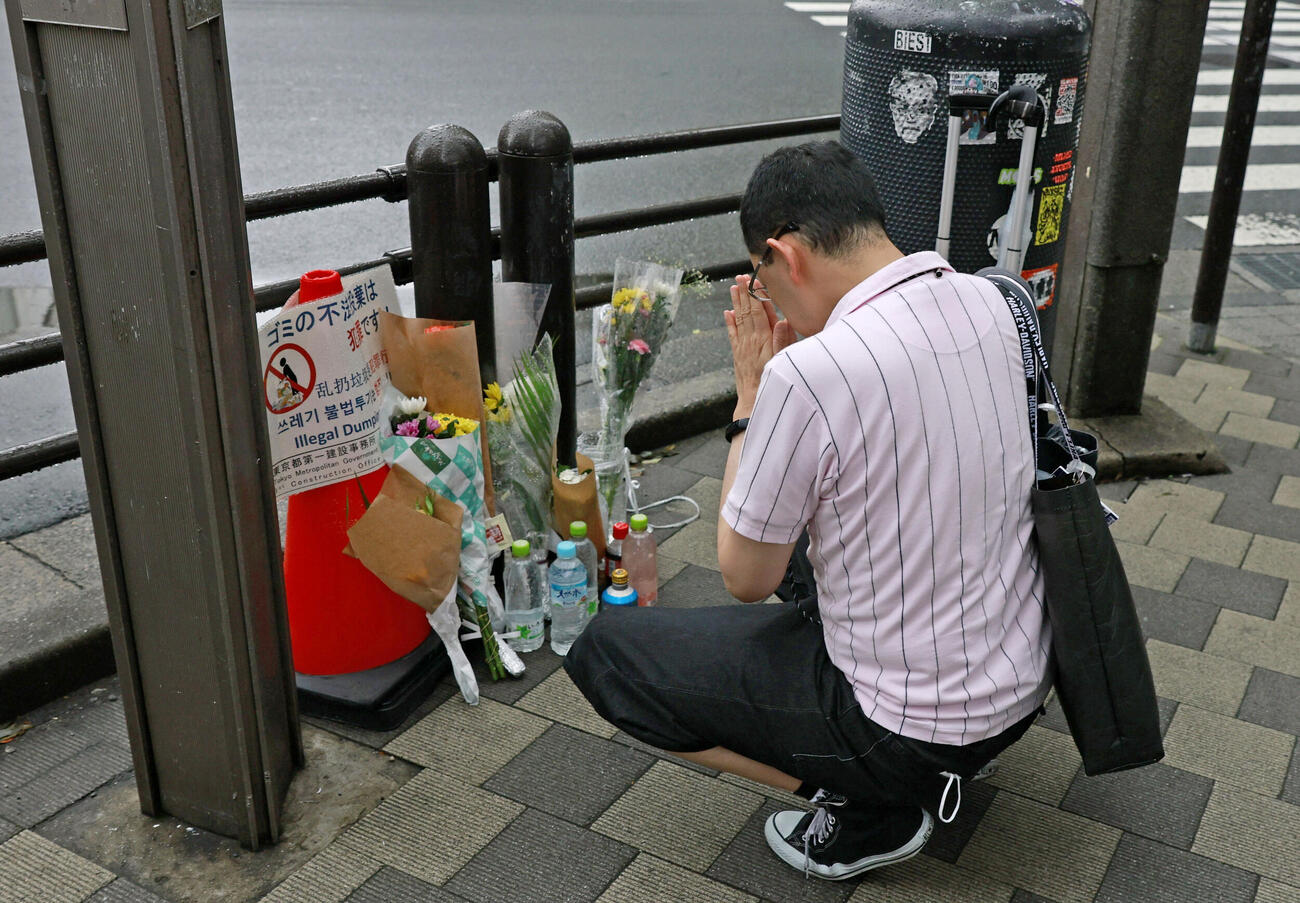 東京・秋葉原の無差別殺傷事件現場となった交差点で手を合わせる人＝8日午前（共同）