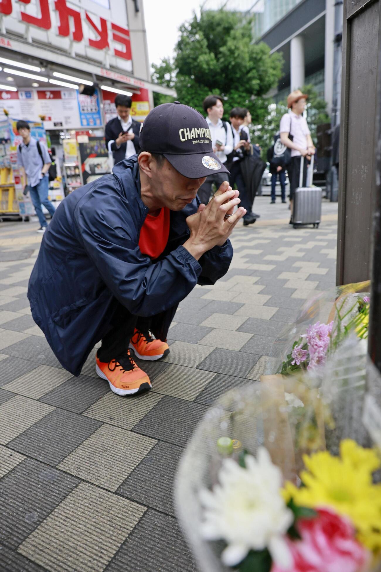 東京・秋葉原の無差別殺傷事件現場となった交差点で手を合わせる人＝8日午前（共同）