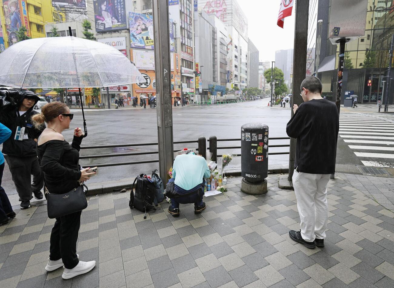 無差別殺傷事件の現場となった東京・秋葉原の交差点で、事件発生時刻に合わせて祈る人たち＝8日午後0時30分（共同）