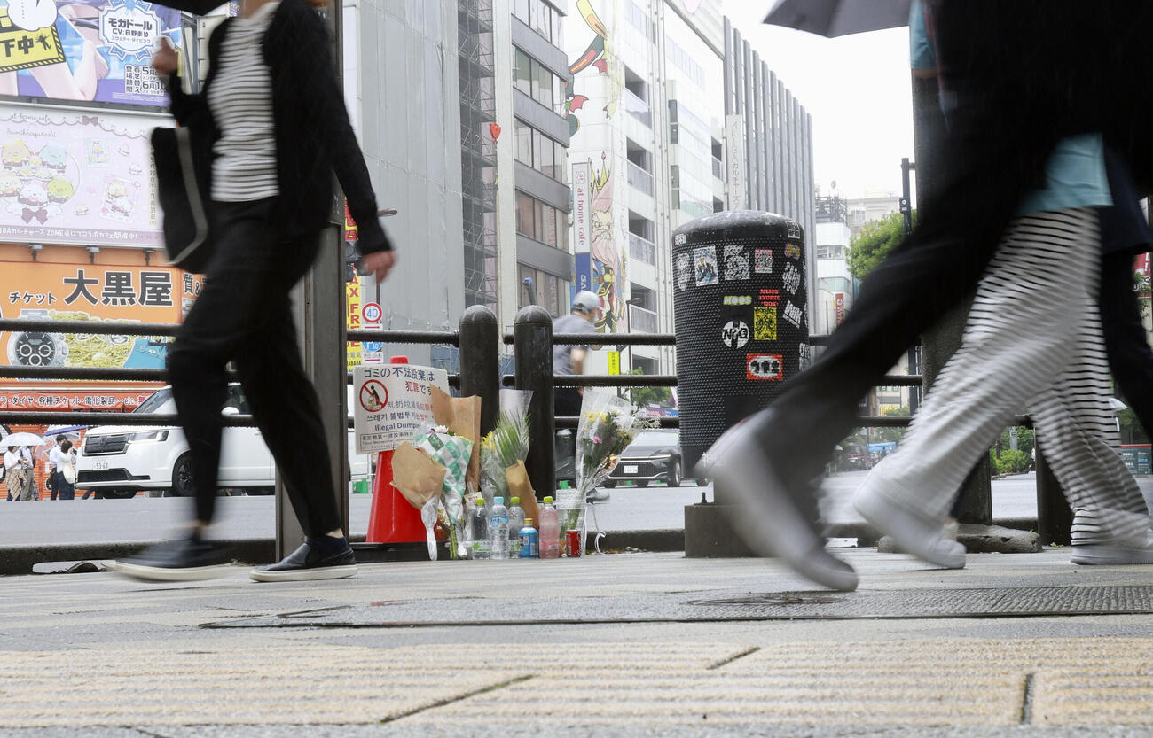 東京・秋葉原の無差別殺傷事件現場となった交差点付近を行き交う人たちと手向けられた花束＝8日午前、東京・秋葉原（共同）