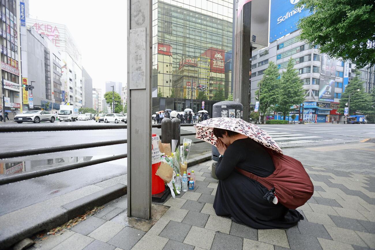 東京・秋葉原の無差別殺傷事件現場となった交差点で手を合わせる人＝8日午前（共同）
