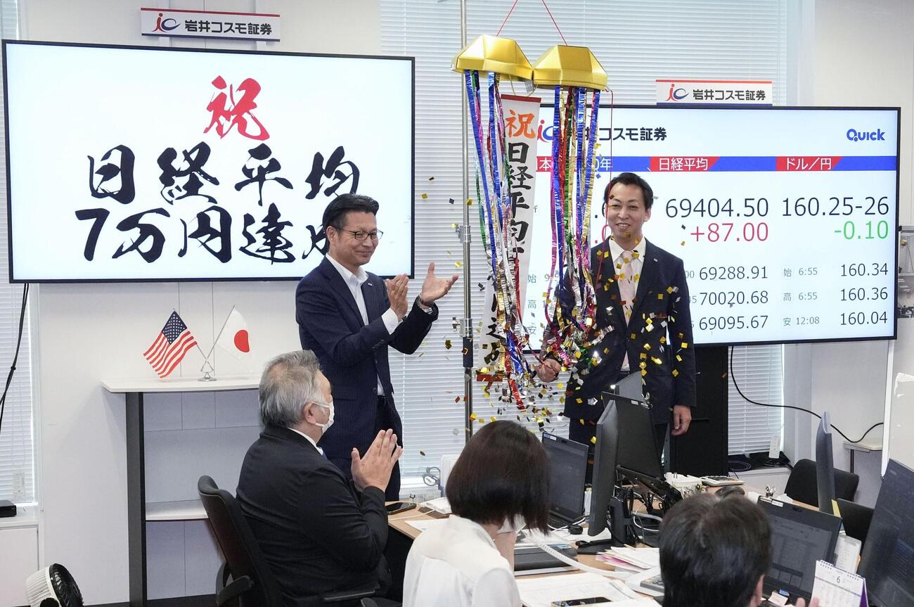 日経平均株価が取引時間中に初めて7万円を超え、くす玉を割って祝福する岩井コスモ証券の社員ら（共同）