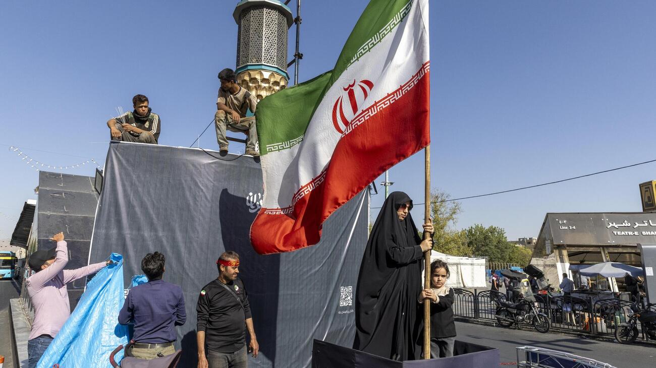 イラン・テヘランで国旗を掲げる女性（ゲッティ＝共同）