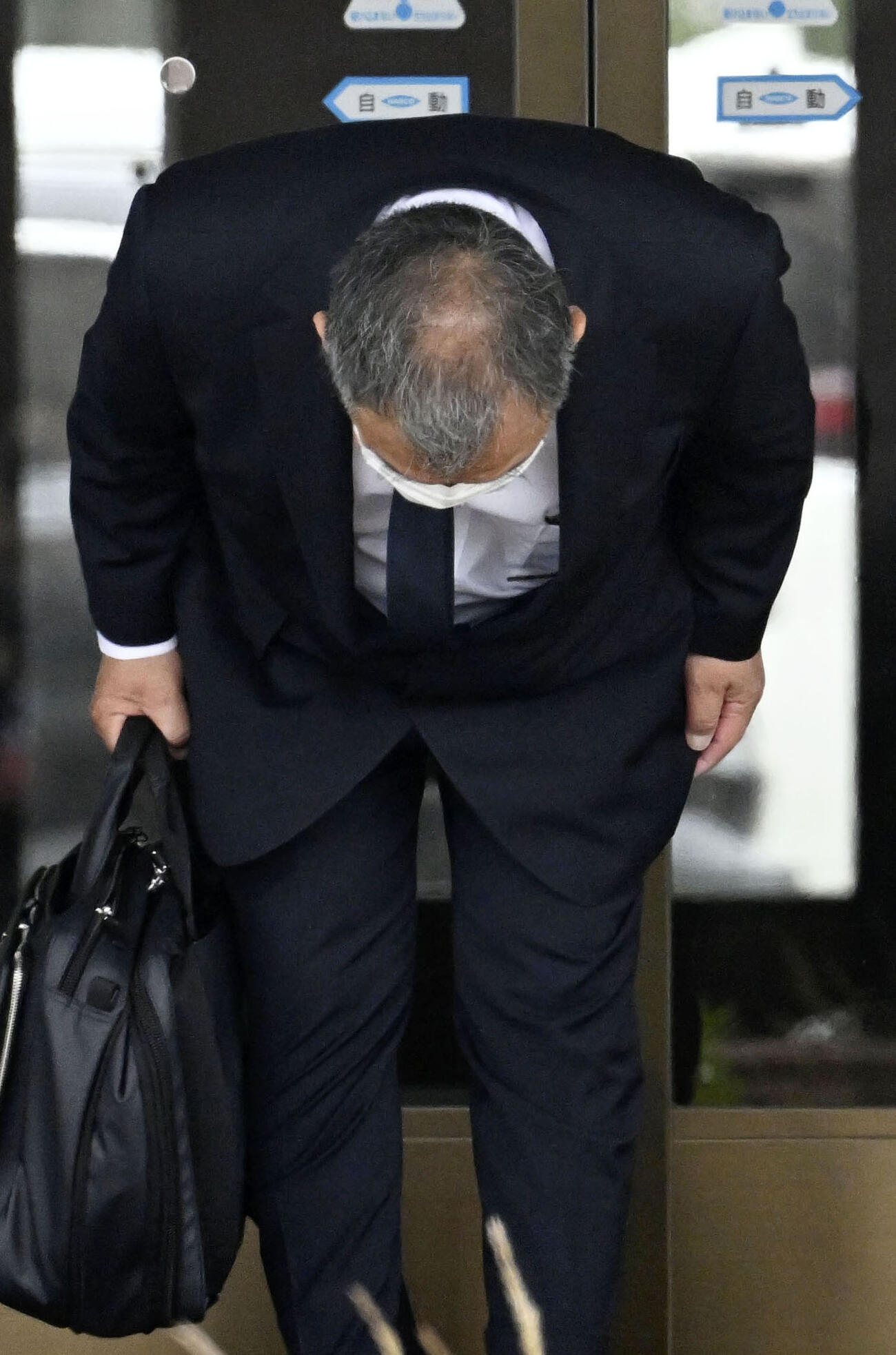 一礼して釧路地裁に入る桂田精一被告