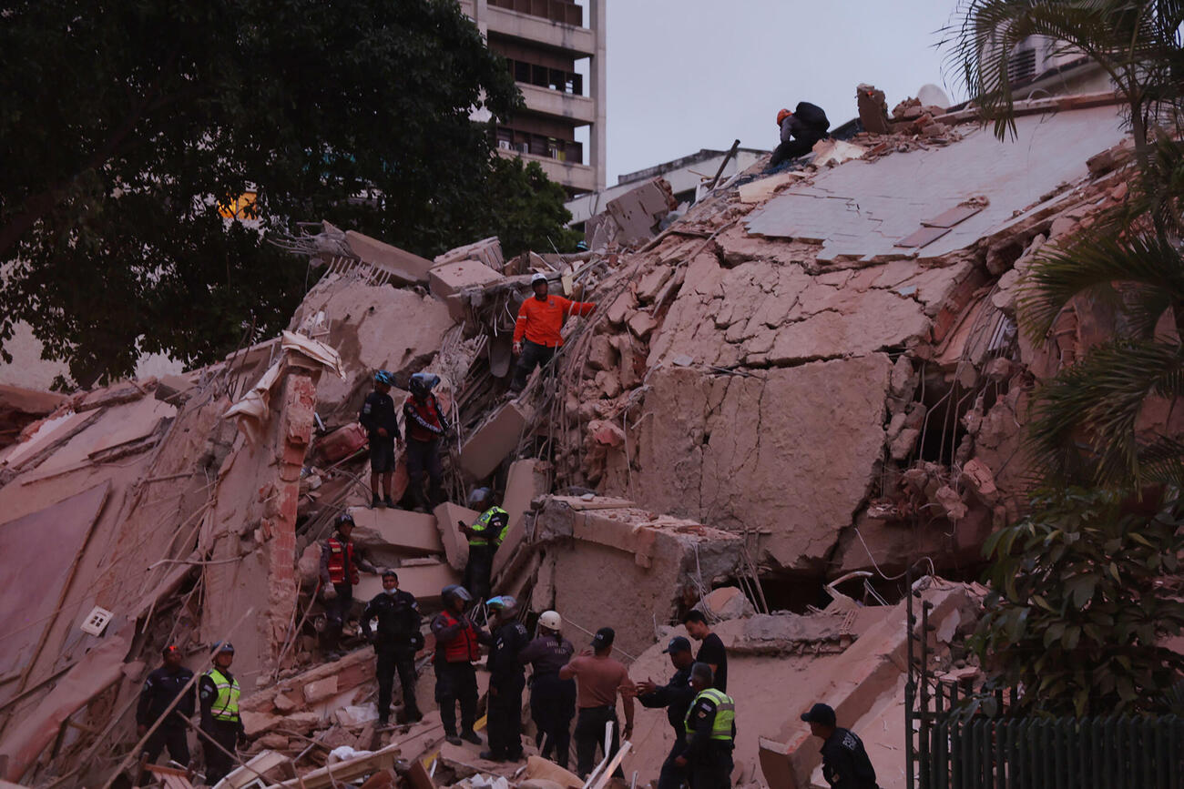 24日、ベネズエラの首都カラカスで、地震の後に壊れた建物に駆けつけた救急隊員ら（ゲッティ＝共同）