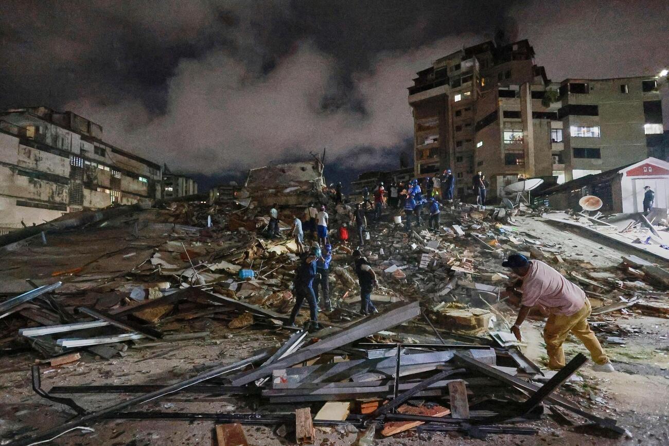 24日、ベネズエラの首都カラカスで、地震後に捜索活動をする救助隊員ら（AP＝共同）