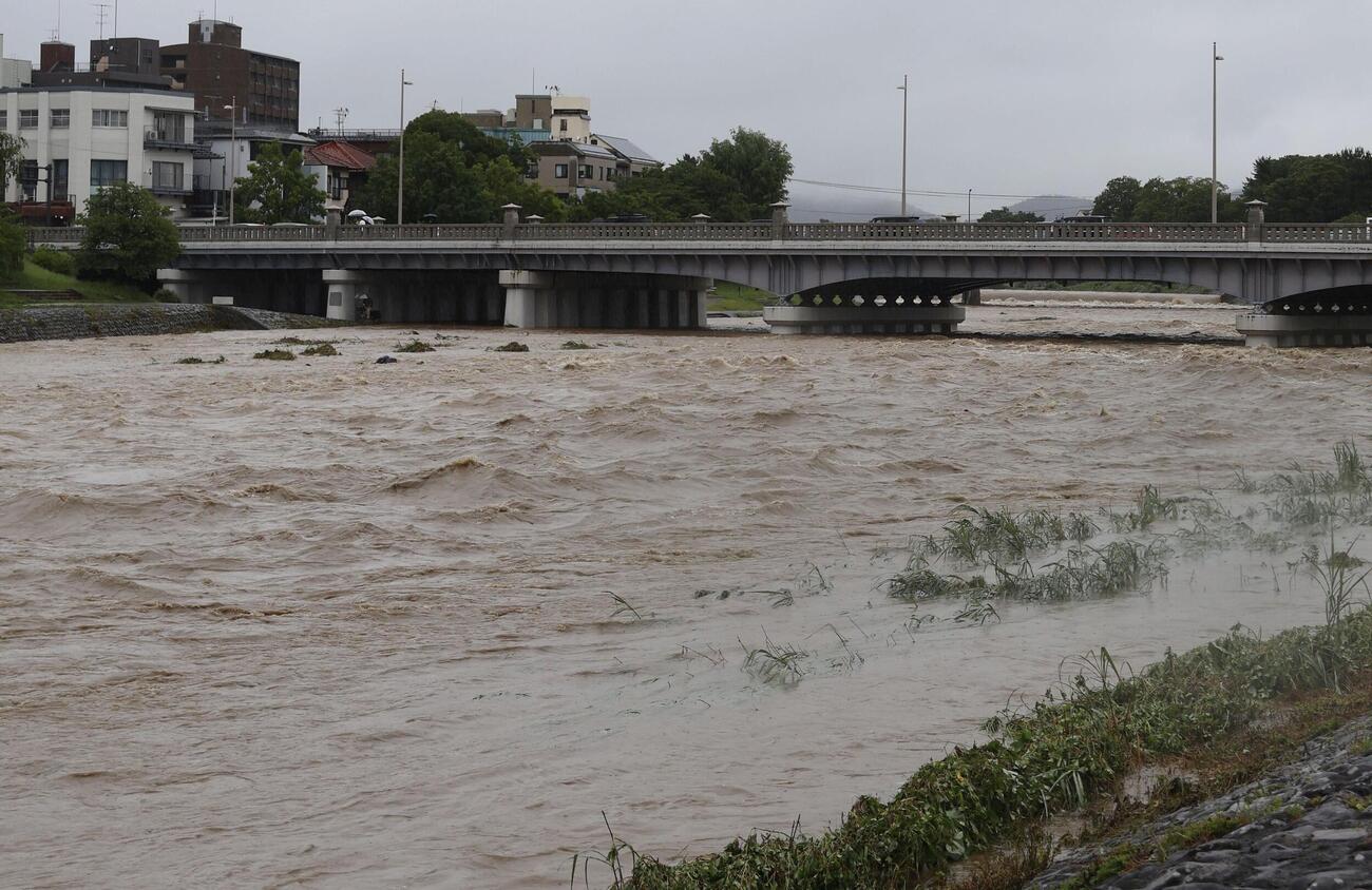 大雨で増水し、激しく流れる鴨川。奥は賀茂大橋＝26日午前9時4分、京都市左京区（共同）