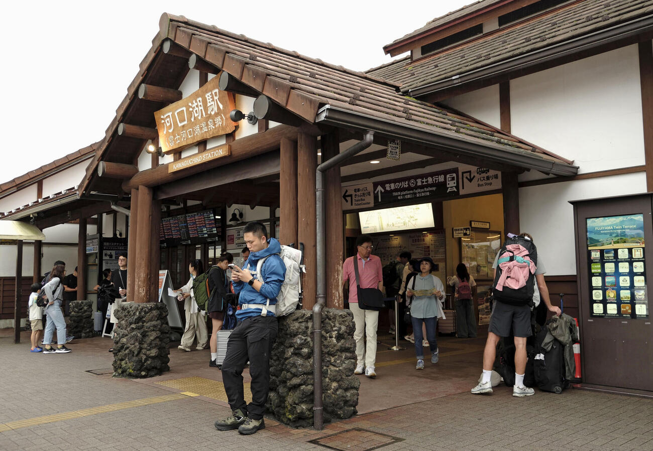 高速バスが運休し、富士急行線河口湖駅で情報を確認する観光客ら＝27日午前9時半ごろ、山梨県富士河口湖町