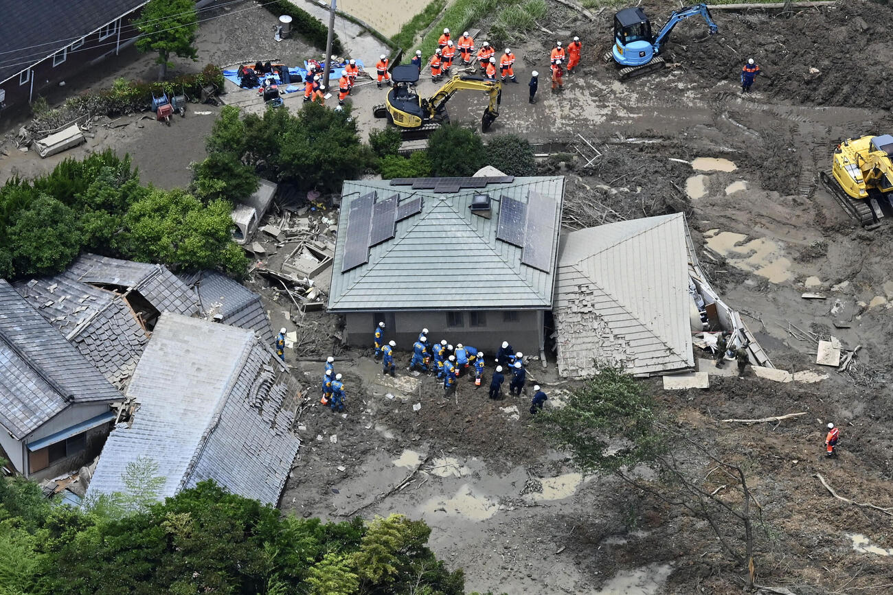 土砂崩れに巻き込まれた山口県平生町の住宅で、捜索と救助に当たる警察官ら＝27日午前11時39分（共同通信社ヘリから）