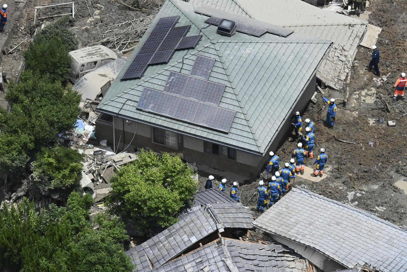 土砂崩れに巻き込まれた住宅を捜索する警察官ら＝27日午前11時35分、山口県平生町（共同通信社ヘリから）