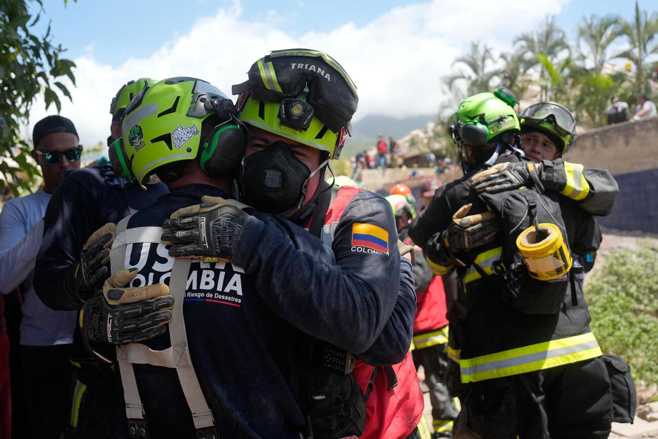 27日、ベネズエラ・ラグアイラで11歳の少年を救出後、喜び合うコロンビアの救助隊メンバーら（AP＝共同）