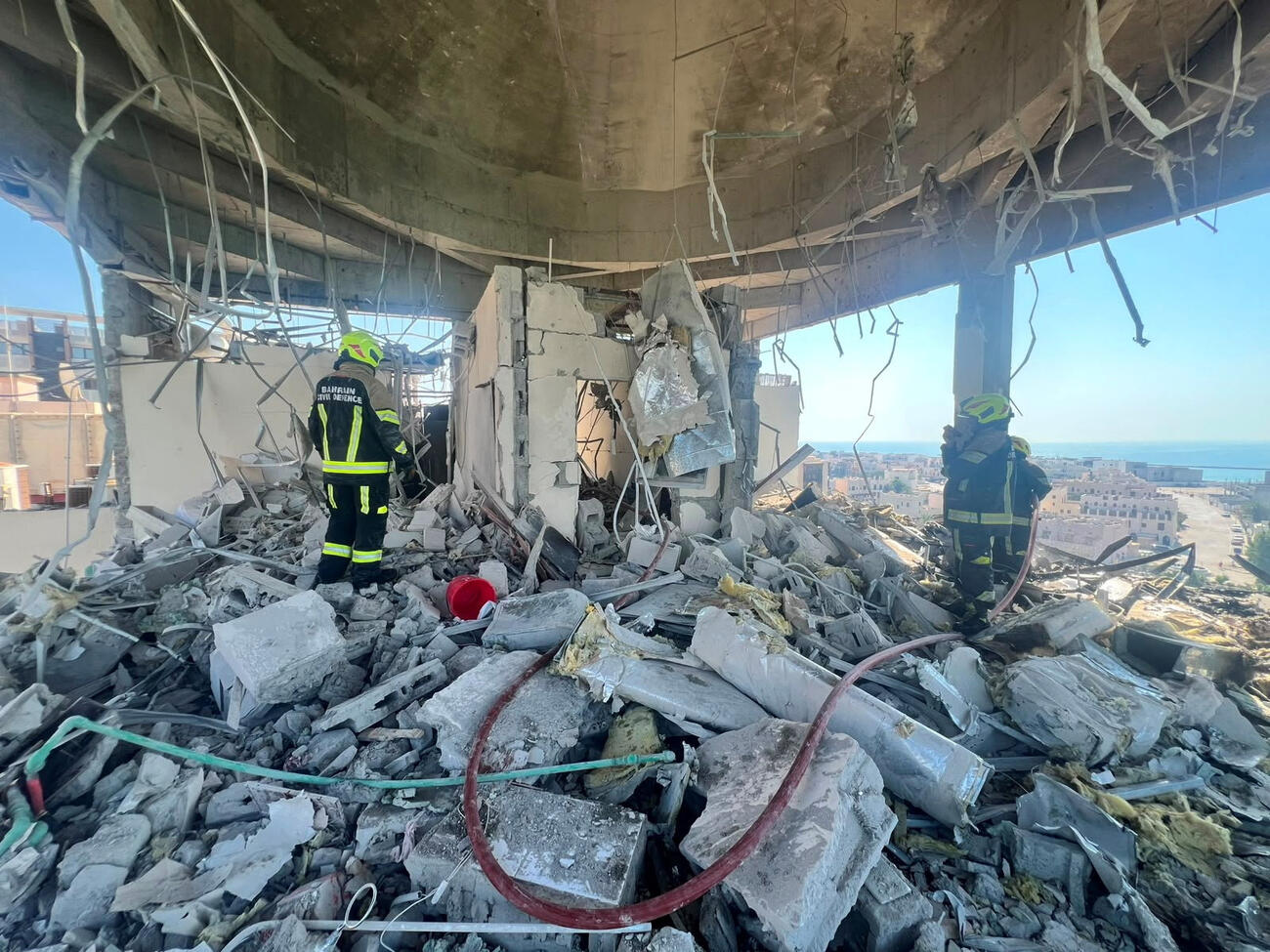 28日、バーレーン・ムハラクで、イランの無人機攻撃を受けた集合住宅で作業に当たる救助隊員ら（バーレーン警察提供・ロイター＝共同）