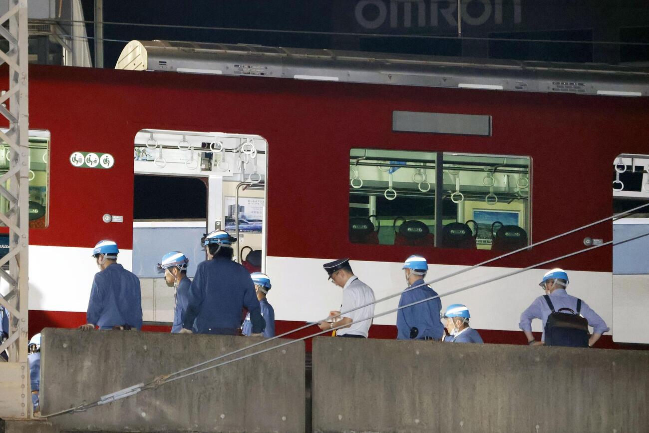 脱線した近鉄京都線の車両付近で作業する人たち＝30日午前0時46分、京都市（共同）