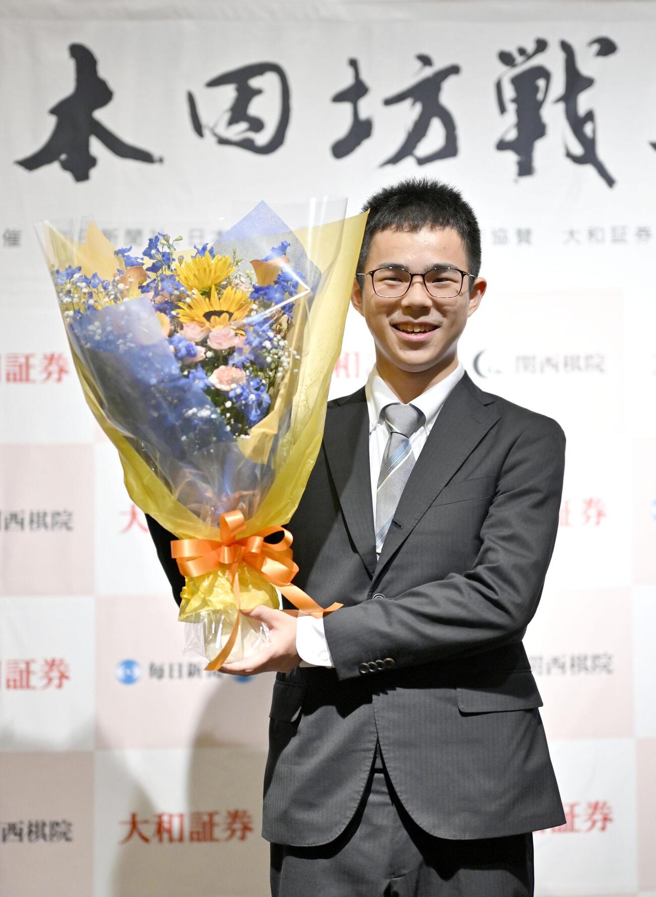 最年少記録で本因坊のタイトルを獲得し、花束を手に笑顔の福岡航太朗新本因坊＝1日午後、甲府市（共同）