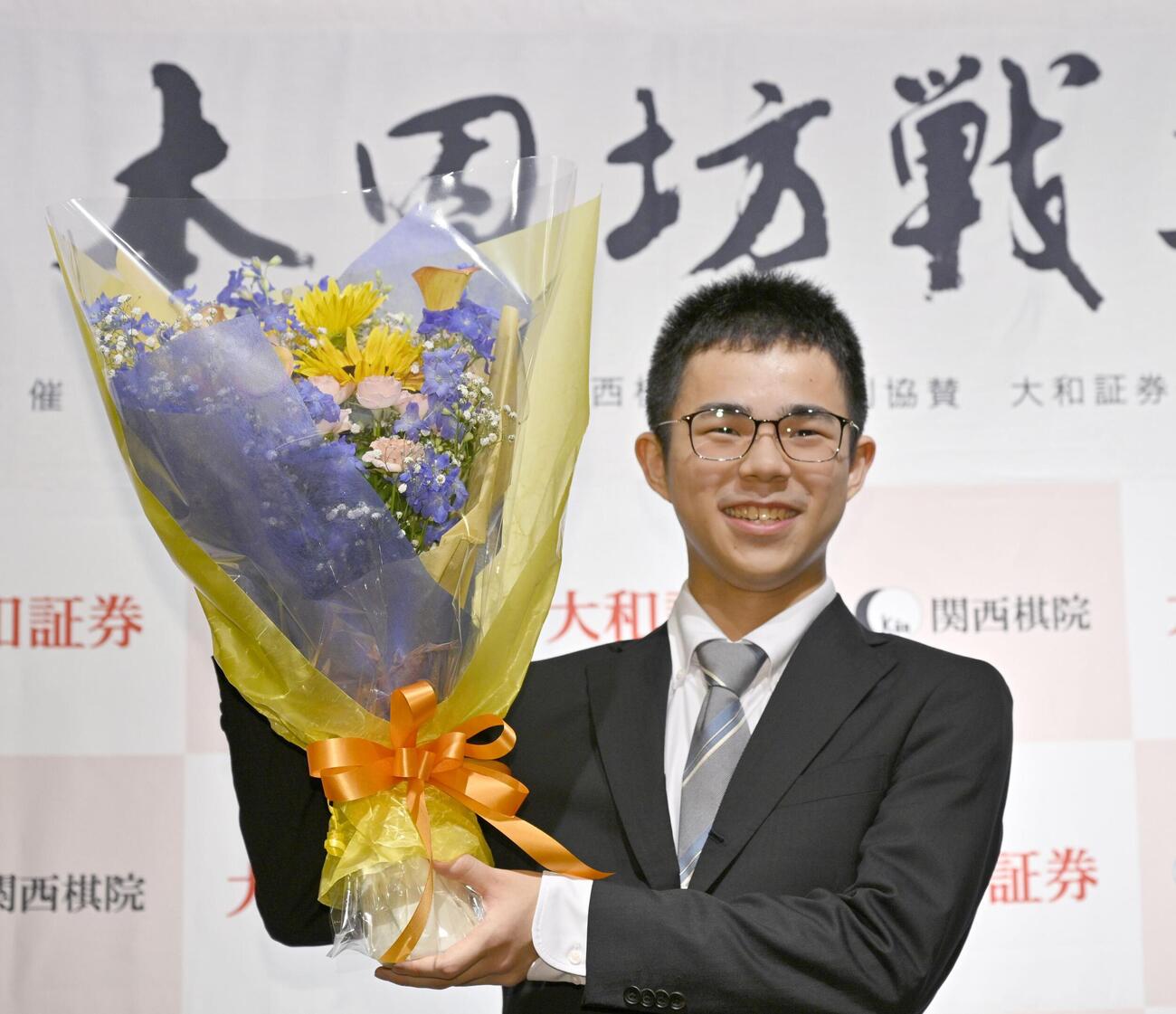 最年少記録で本因坊のタイトルを獲得し、花束を手に笑顔の福岡航太朗新本因坊＝1日午後、甲府市（共同）