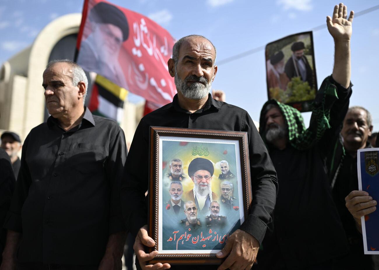 イランの前最高指導者アリ・ハメネイ師の国葬で、肖像を手にする男性ら＝4日（共同）