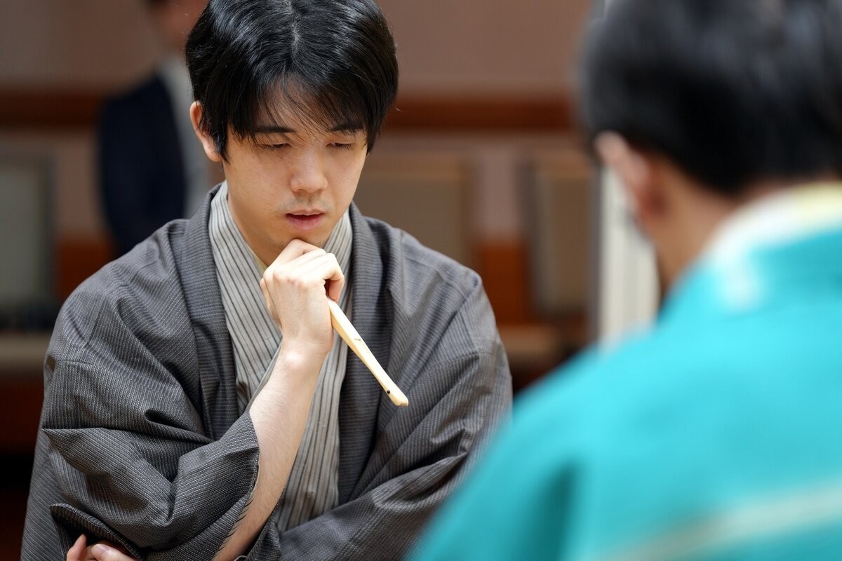 扇子を手に盤面を見つめる藤井聡太王位（日本将棋連盟提供）