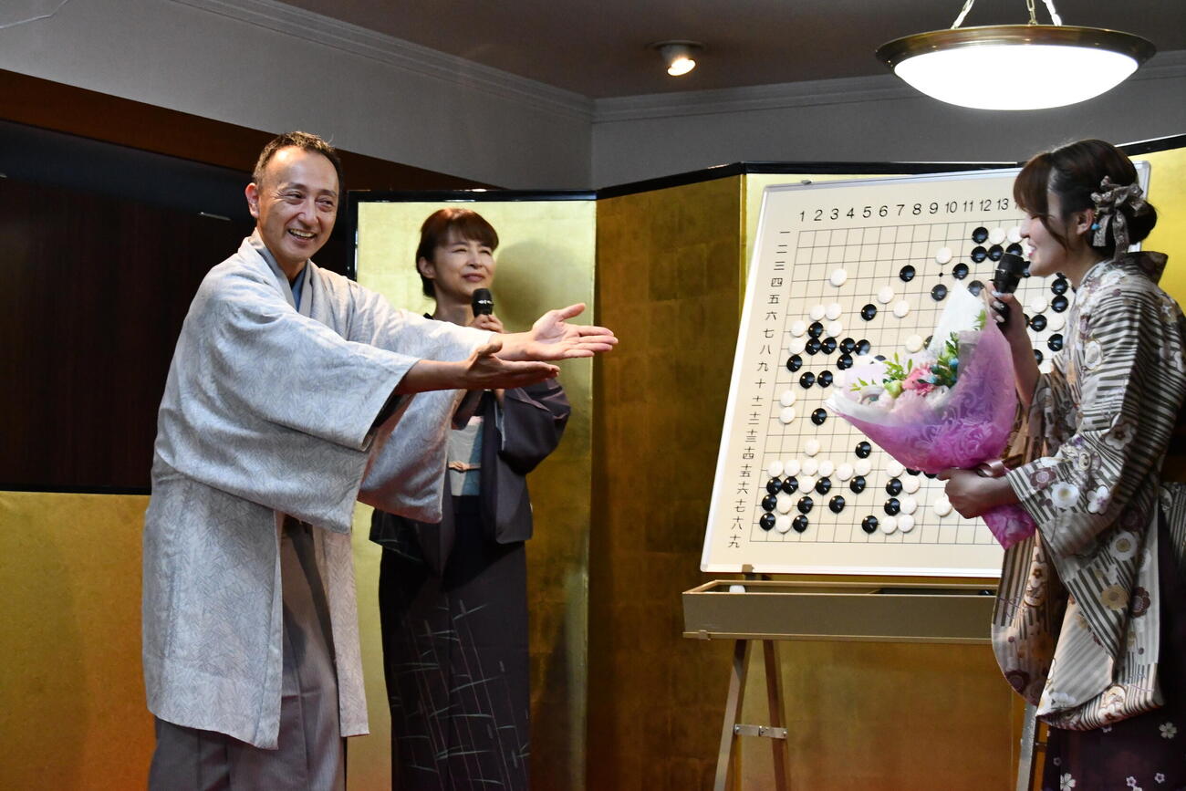 白瀧呉服店の白瀧佐太郎店主（左）から実行委員会代表の木部夏生三段（右）に花束が贈られた（中央は協力棋士の吉原由香里六段）
