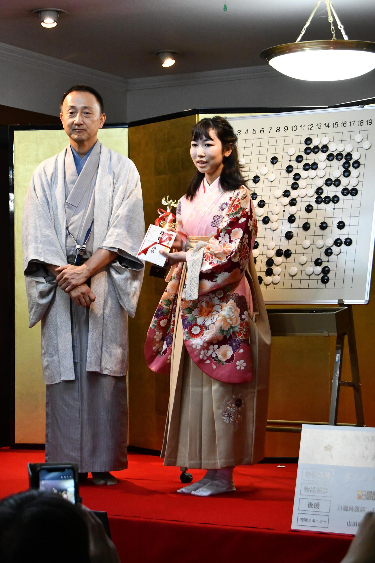 白瀧呉服店の白瀧佐太郎店主（左）から優勝の表彰をされる柳原咲輝二段（右）