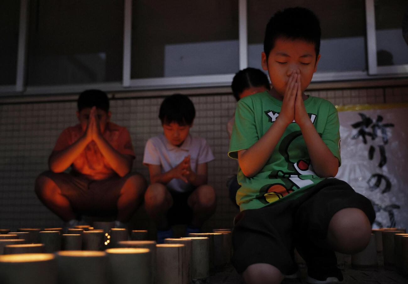 西日本豪雨から8年、竹灯籠の前で手を合わせる子どもたち（共同）
