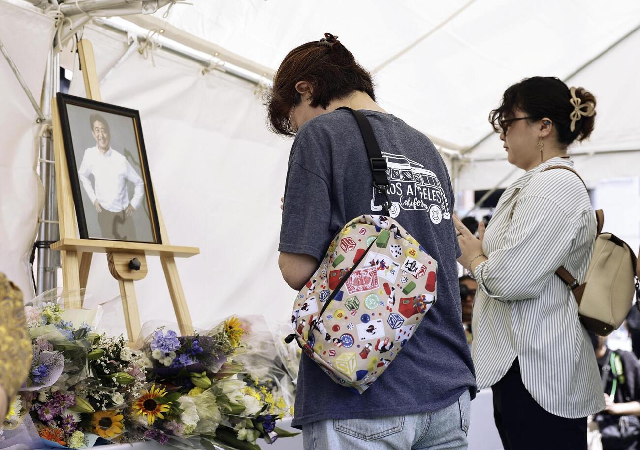安倍元首相銃撃事件から4年、奈良市の現場付近の献花台で手を合わせる人たち（共同）