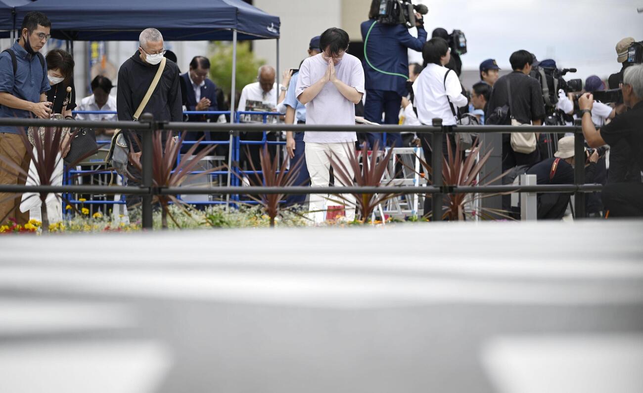 安倍元首相銃撃事件から4年、発生時刻に合わせて現場付近で黙とうする人たち（共同）