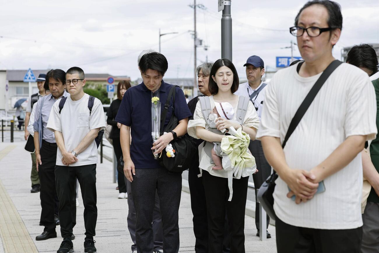 安倍元首相銃撃事件から4年、発生時刻に合わせて現場付近で黙とうする人たち＝8日午前、奈良市