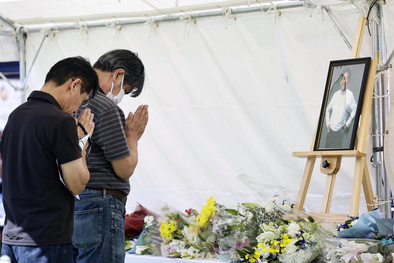 安倍元首相銃撃事件から4年、現場付近の献花台で手を合わせる人たち（共同）
