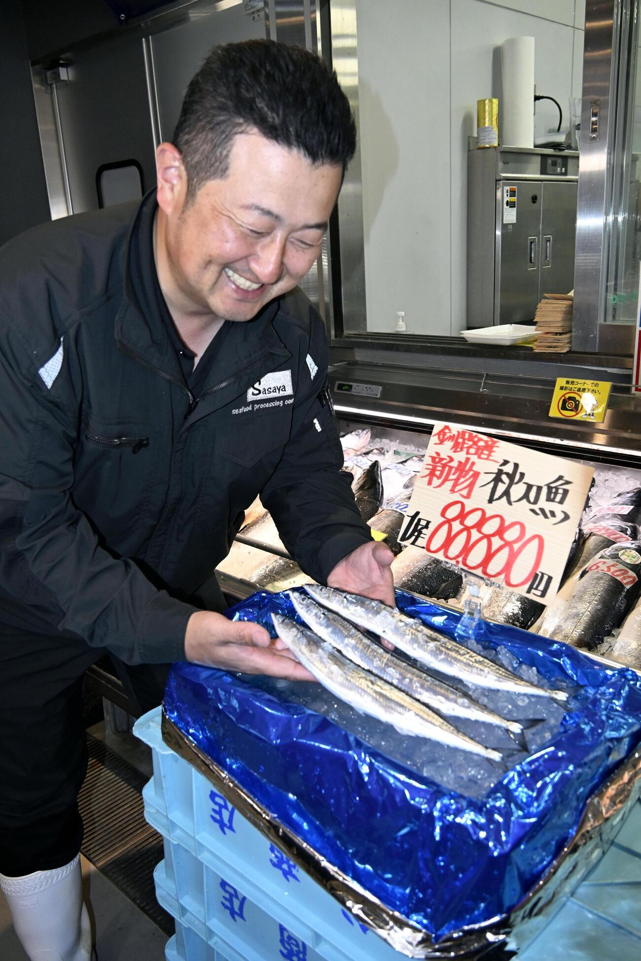 1匹8万8880円の値が付いたサンマを見つめ、笑顔を見せる水産加工会社マルサ笹谷商店の笹谷剛社長（共同）
