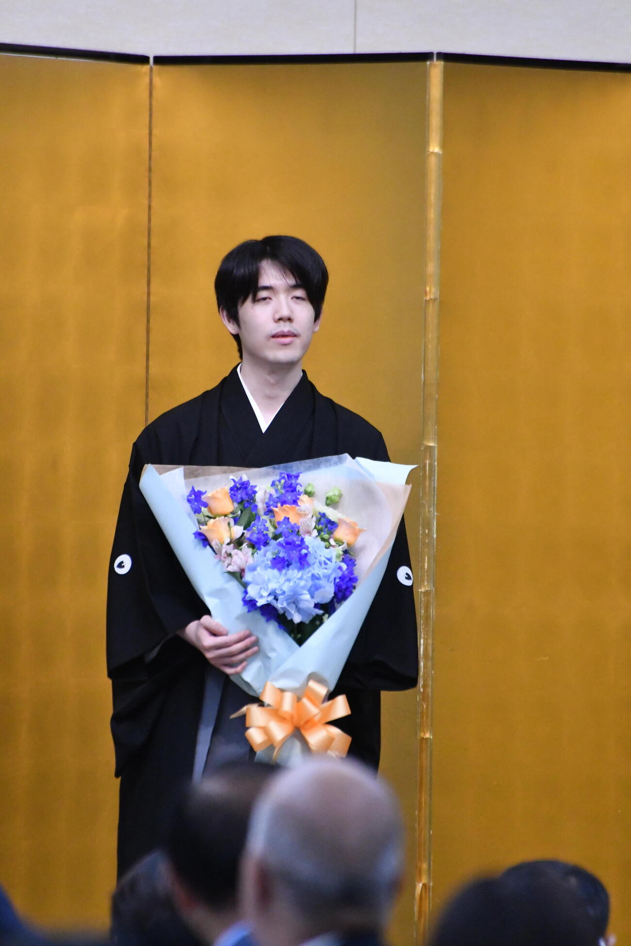 藤井聡太王将は京都・伏見稲荷大社の黒田長宏権宮司から贈られた花束を手にする