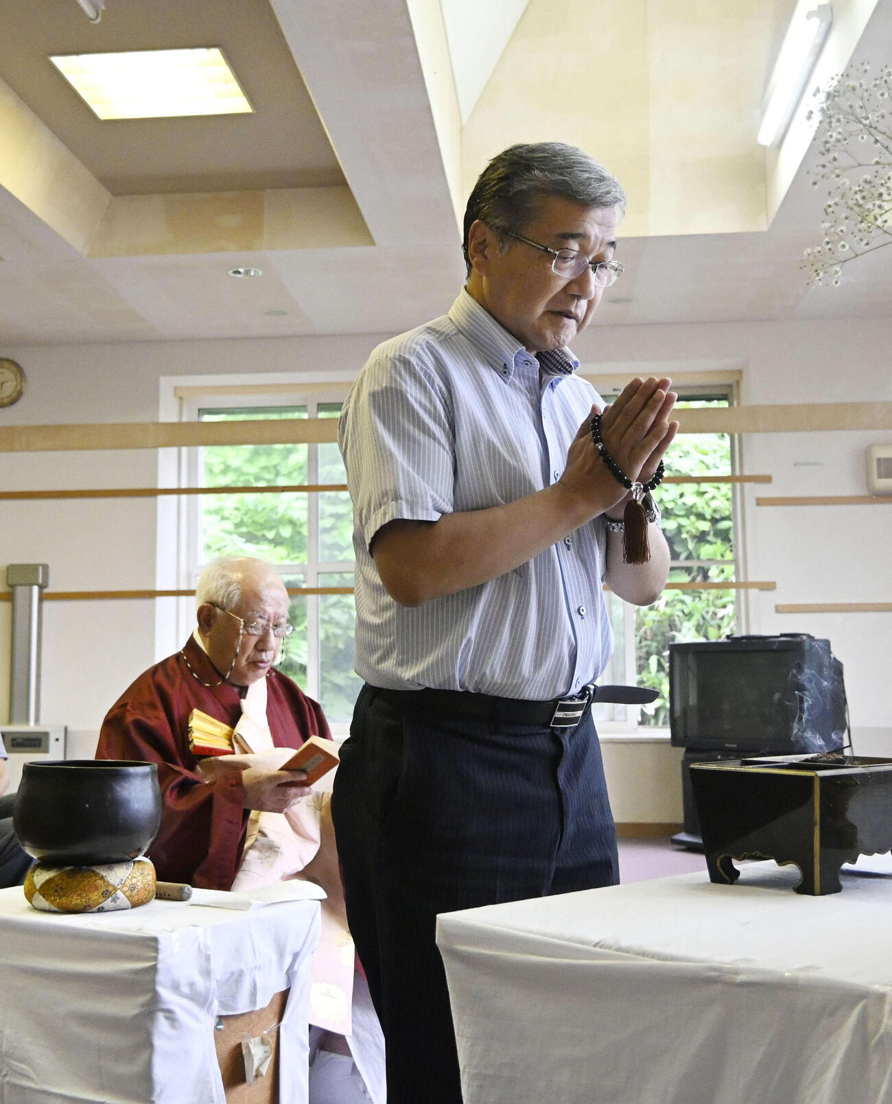 祭壇の前で手を合わせる遺族会長の阿部元大さん（右）＝12日午後、北海道奥尻町(共同)
