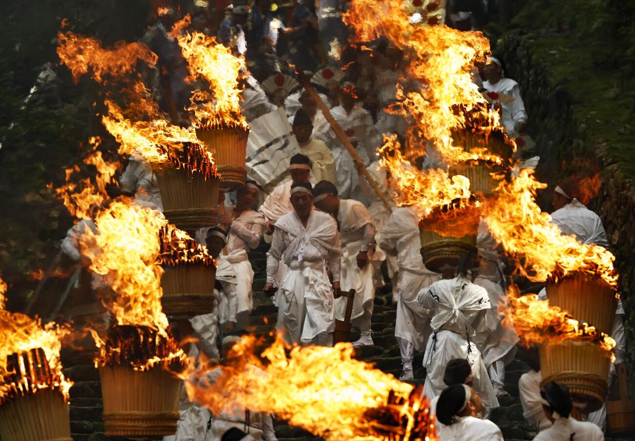 世界遺産・熊野那智大社で開かれた例大祭「那智の扇祭り」。白装束の氏子たちが燃えさかる大たいまつを担ぎ練り歩いた（共同）