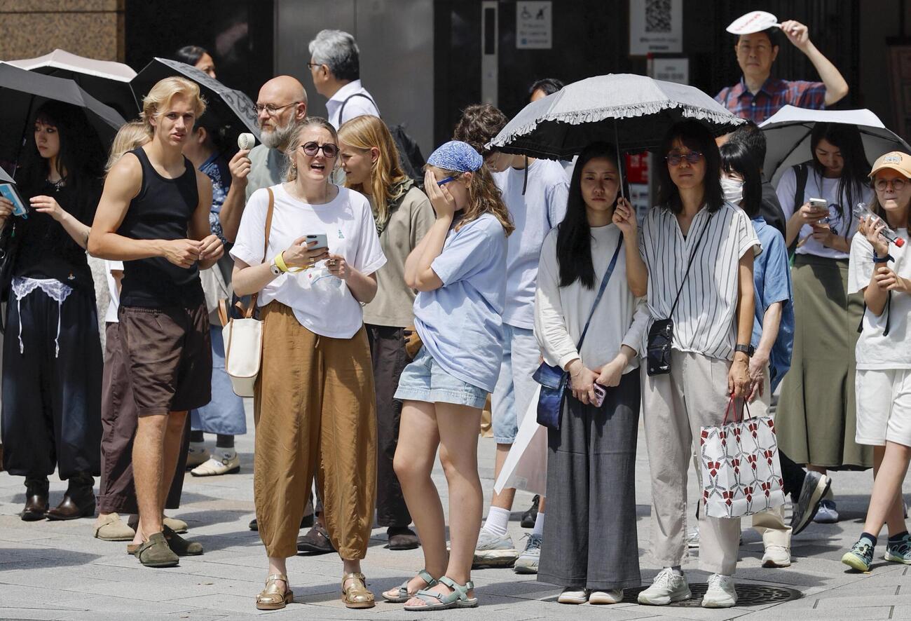 東京・銀座で日傘を差して信号待ちする人たち（共同）