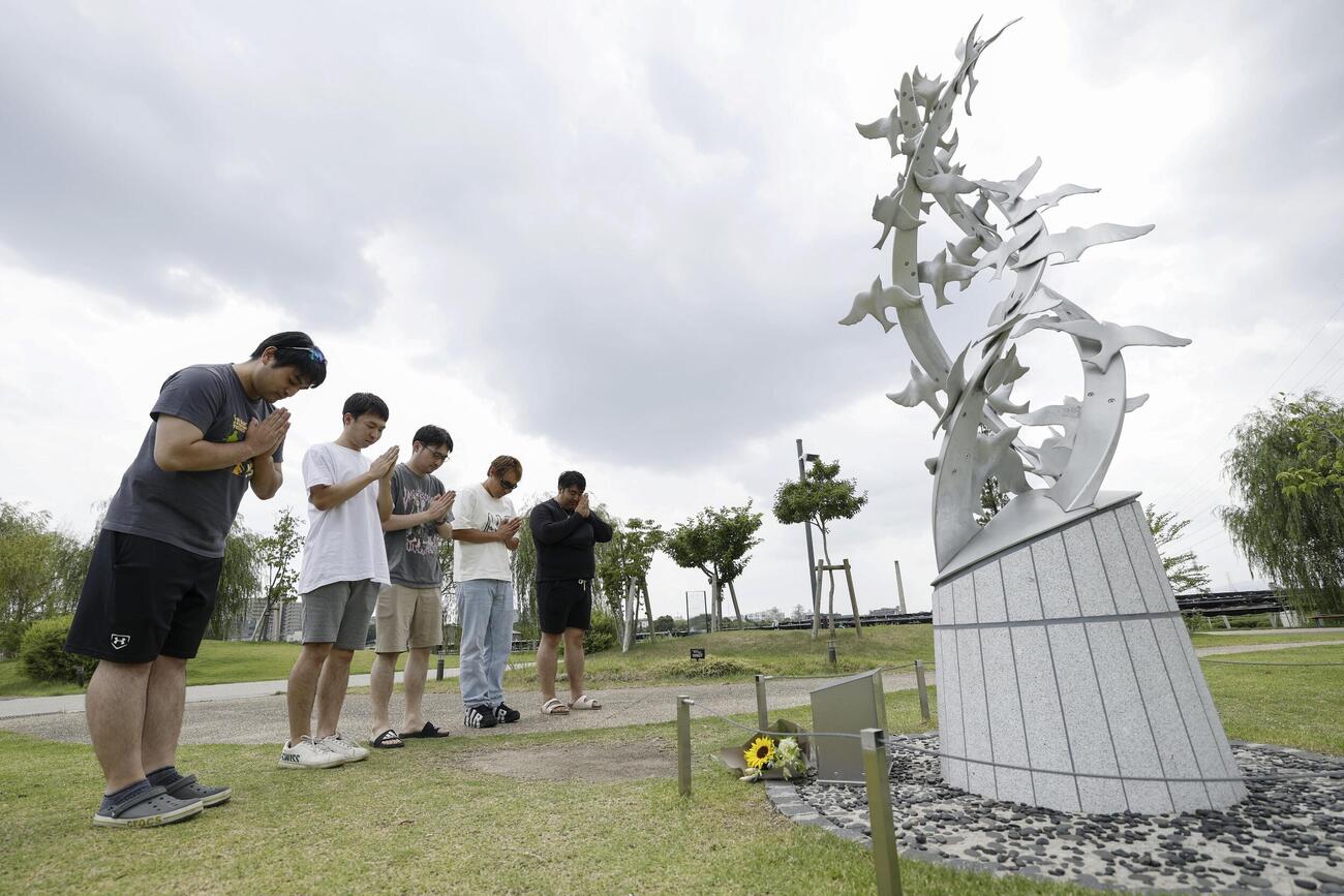 36人が死亡した京都アニメーション放火事件から7年となり、「志を繋ぐ碑」の前で手を合わせる人たち。「京都アニメーションの作品で友人との仲が深まった。感謝しています。二度とあってはならない事件です」と話した（共同）