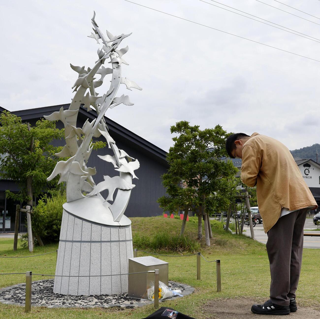 京都アニメーション放火事件から7年となり、「志を繋ぐ碑」の前で手を合わせる男性＝18日午前、京都府宇治市（共同）