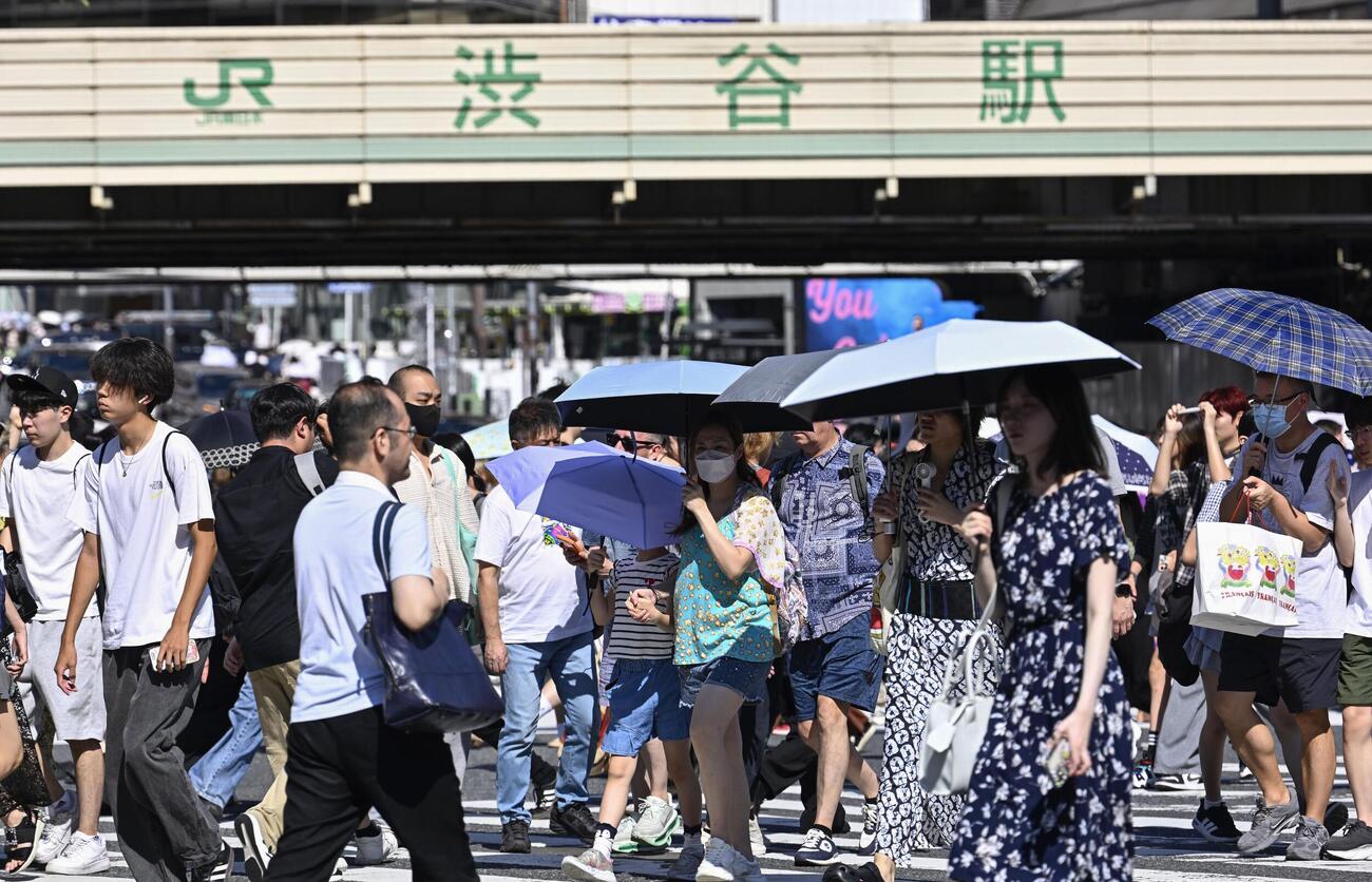 今年初の猛暑日となった東京・渋谷を歩く人たち。気象庁は東海、関東甲信が梅雨明けしたとみられると発表した（共同）