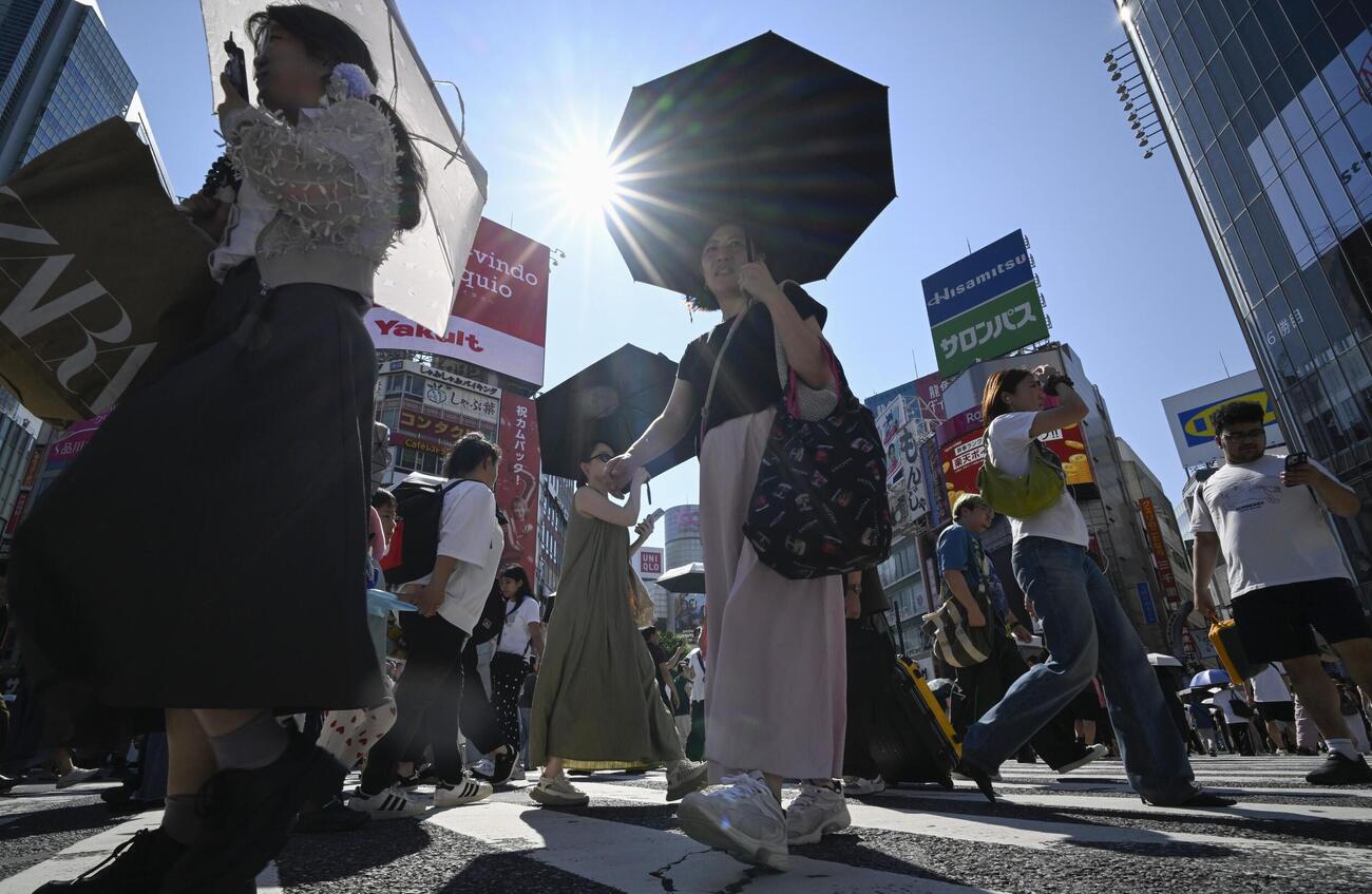 今年初の猛暑日となった東京・渋谷を歩く人たち。気象庁は東海、関東甲信が梅雨明けしたとみられると発表した（共同）