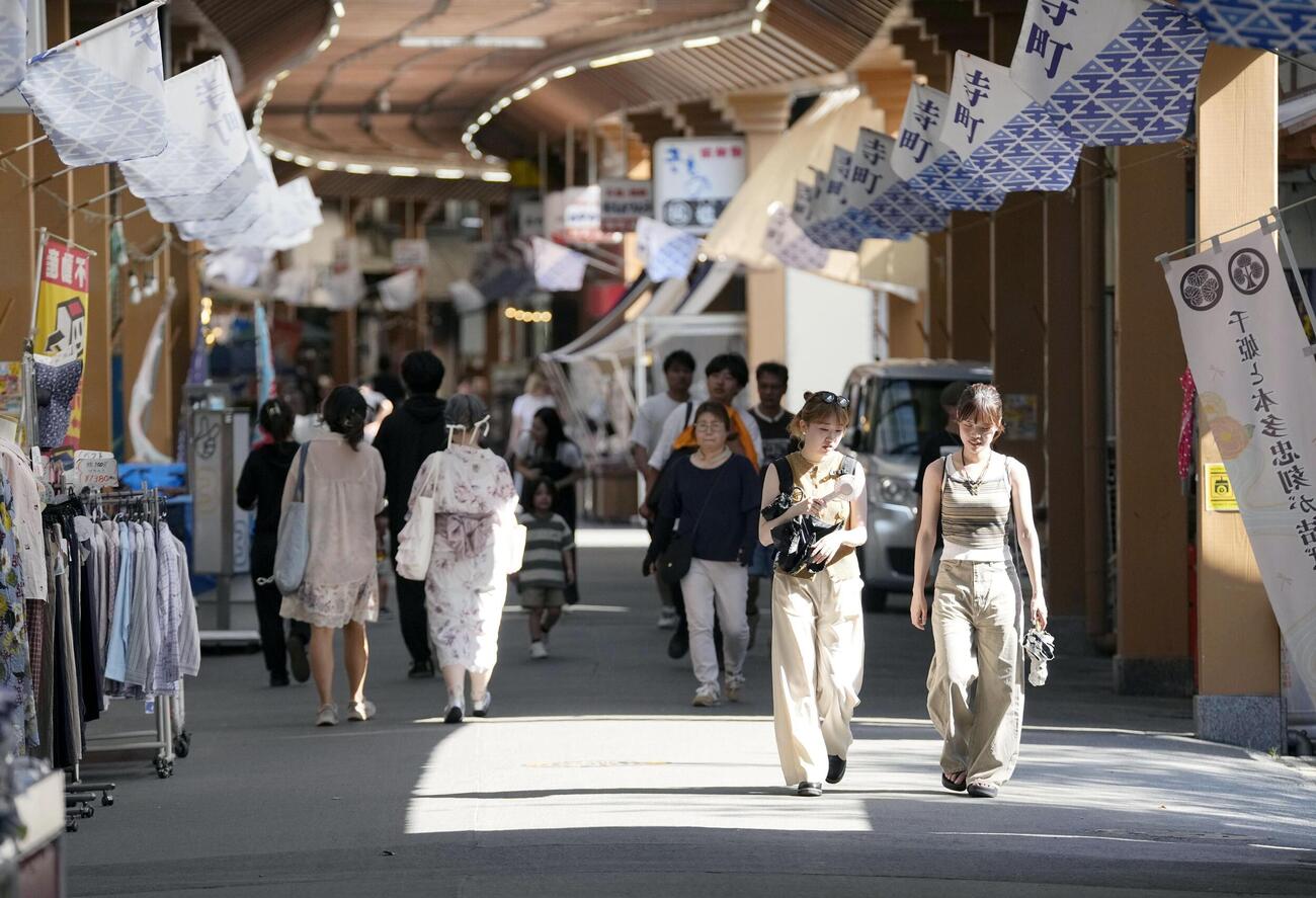 酷暑日となった三重県桑名市で、商店街を歩く人たち＝25日午後(共同)