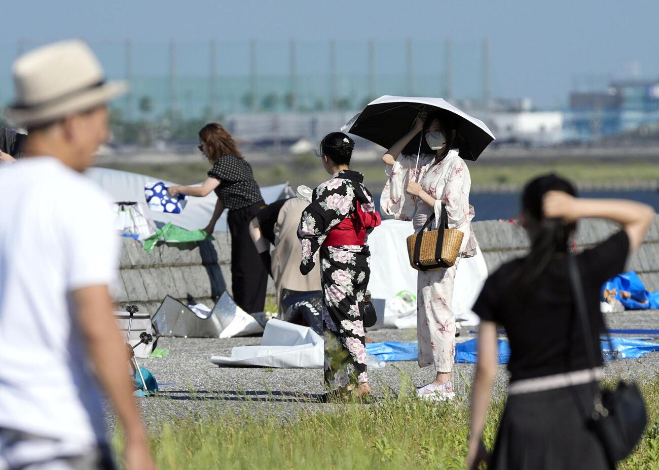酷暑日となった三重県桑名市で、花火大会の会場周辺に集まった人たち＝25日午後(共同)