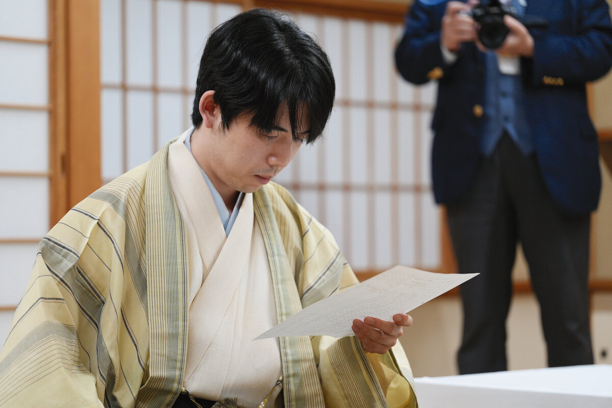 初日の指し手と消費時を棋譜で確認する藤井聡太王位（日本将棋連盟提供）