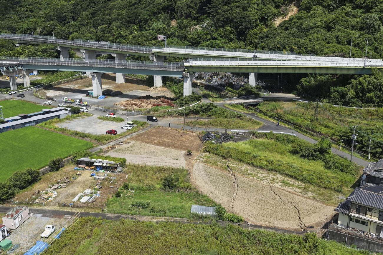 地震の影響で損傷した南九州自動車道（奥）。周辺には地割れが起きているのが確認できる＝29日午後2時25分、熊本県八代市（ドローンから）（共同）